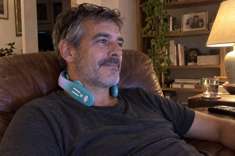 Hombre en su sillón viendo la tele con el masajeador cervical puesto